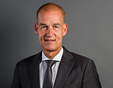 Carsten Cramer – Geschäftsführer – in dunklem Anzug mit dunkler Krawatte schaut direkt in die Kamera (Foto)