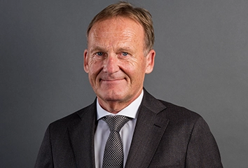 Hans-Joachim Watzke – Vorsitzender der Geschäftsführung – in dunklem Anzug mit dunkler Krawatte schaut direkt in die Kamera (Foto)