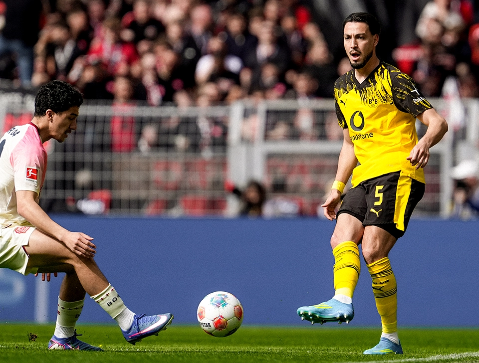 Bensebaini spielt einen Pass nahe einer Auslinie, ein Leverkusen Spieler versucht den Ball abzufangen (Foto)